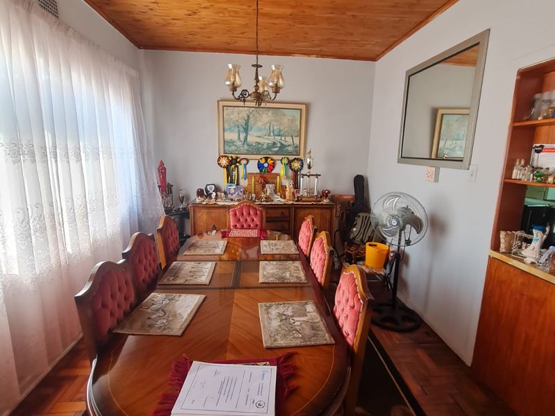 A traditional dining room featuring a warm wooden ceiling, classic parquet flooring, and built-in shelving, providing a cozy space for family meals.