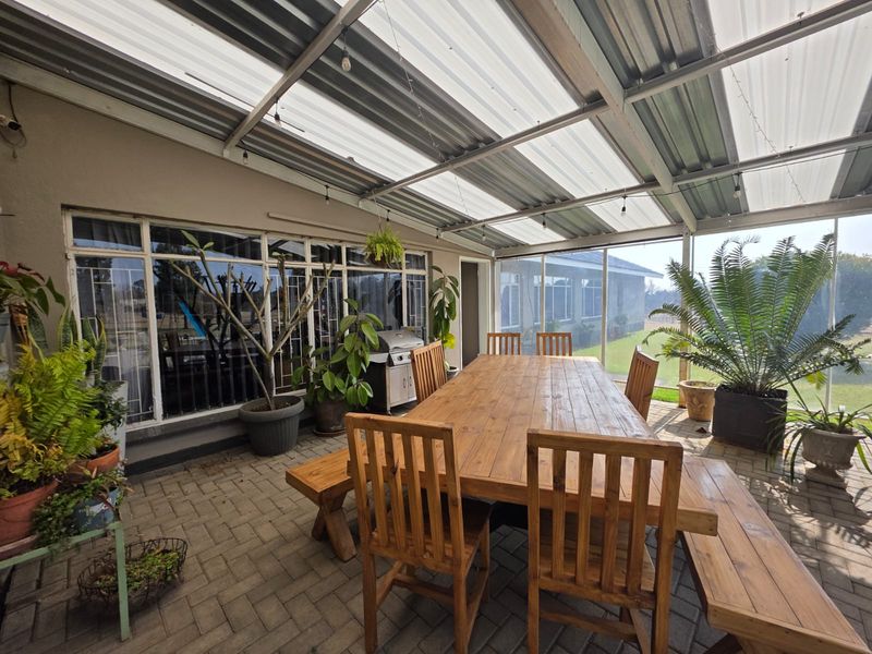 A covered outdoor patio featuring a durable steel frame, corrugated roof, and paved flooring, ideal for alfresco dining and entertaining.