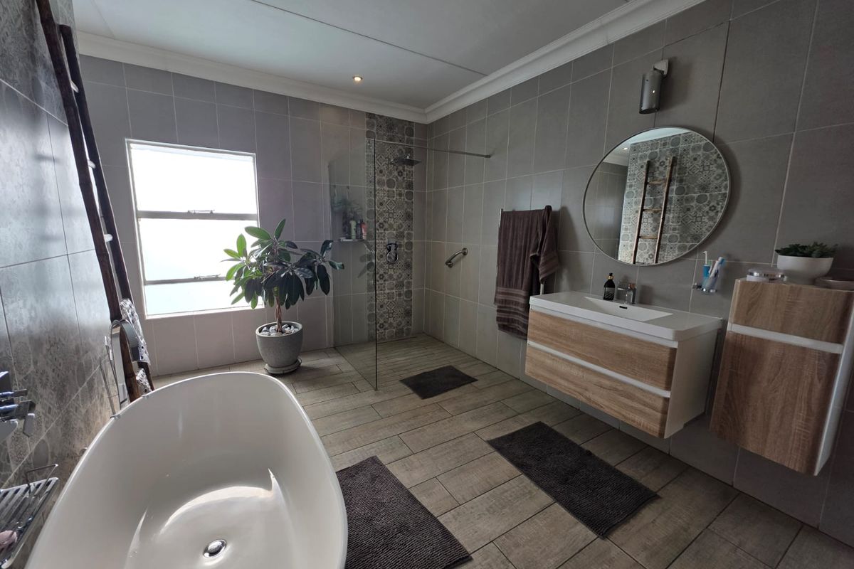 Modern bathroom featuring a freestanding bathtub, a spacious walk-in shower with decorative tile accents, and a contemporary wall-mounted vanity with ample storage.