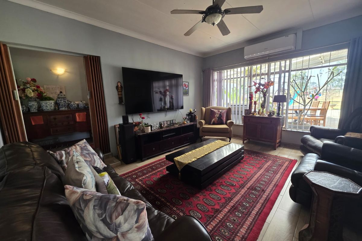 A comfortable living room featuring tiled flooring, a ceiling fan, and a wall-mounted air conditioning unit, with direct access to an outdoor patio area.