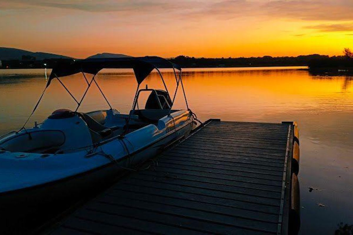 A scenic sunset view over the water featuring a private jetty and boat access, highlighting the tranquil waterfront lifestyle of the property.