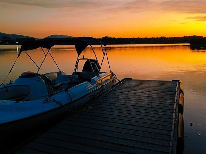 A scenic sunset view over the water featuring a private jetty and boat access, highlighting the tranquil waterfront lifestyle of the property.