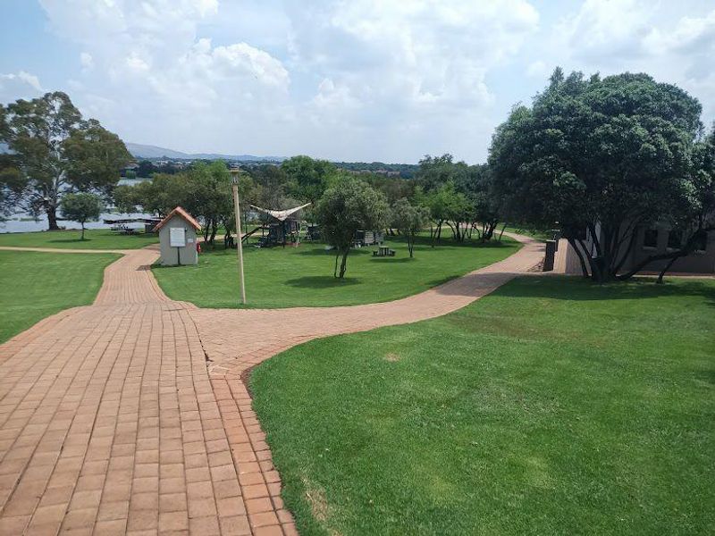 A well-maintained residential garden featuring paved walkways, expansive green lawns, and mature trees, offering a peaceful outdoor environment.