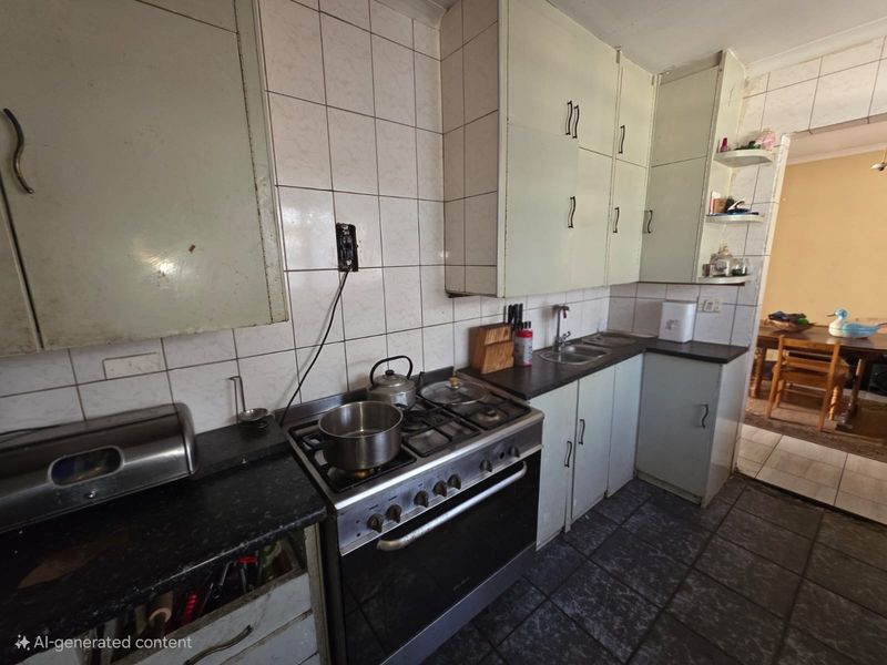 A functional kitchen featuring built-in cabinetry, a gas stove with oven, and tiled surfaces, offering potential for modernization and aesthetic updates.