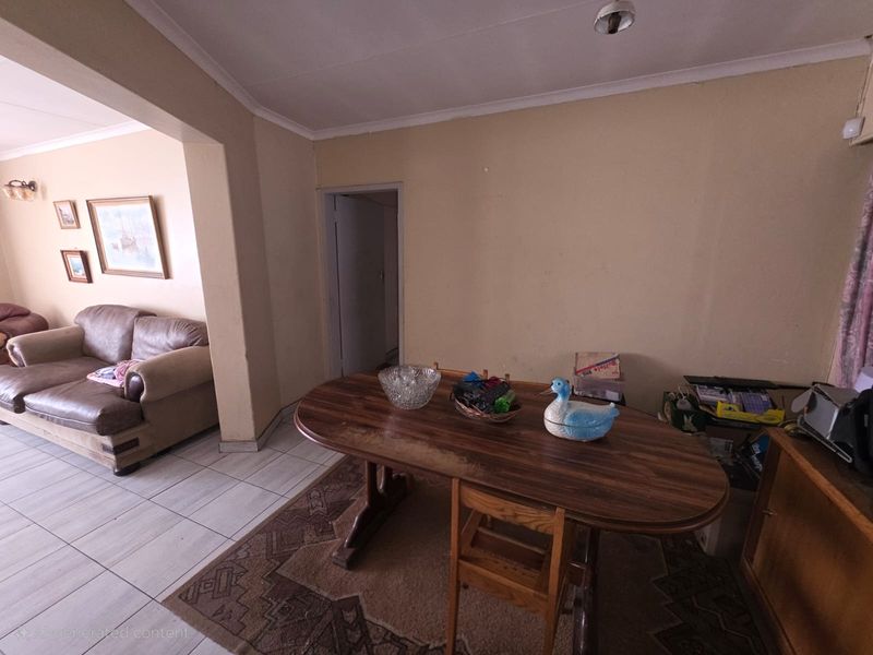 Open plan living and dining area featuring tiled flooring and a connecting archway, providing a functional layout with potential for cosmetic updates.