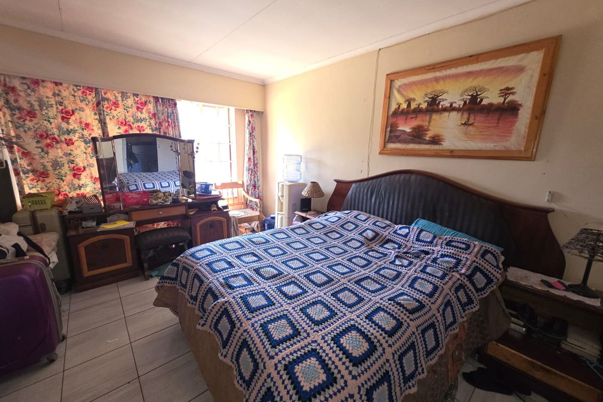 A bedroom featuring tiled flooring and a window with curtains.