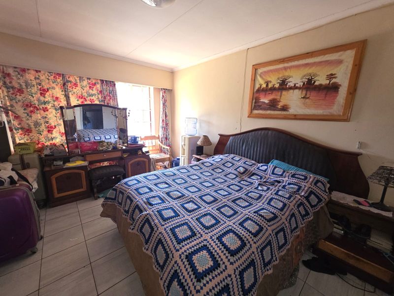 A bedroom featuring tiled flooring and a window with curtains.