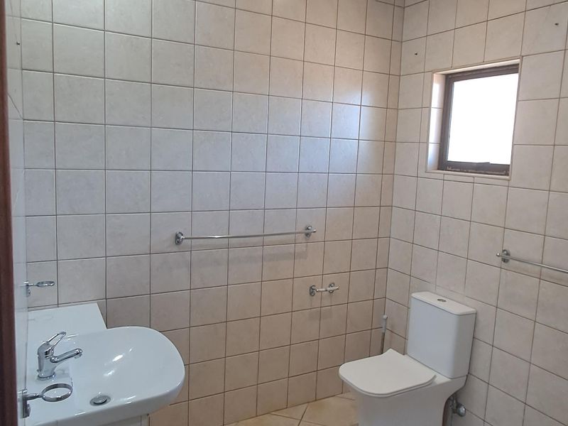 A functional bathroom featuring tiled walls and flooring, a vanity basin, and a standard toilet, offering a clean and practical space.