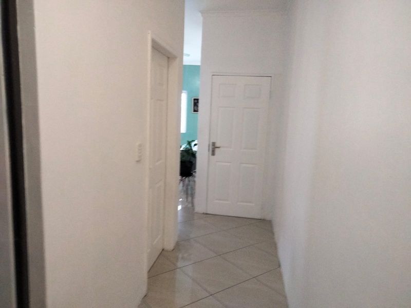 A simple interior hallway featuring tiled flooring and white panel doors leading to other rooms in the townhouse.