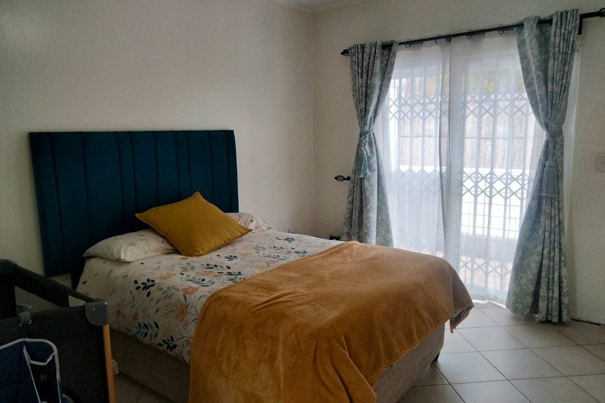 A bedroom featuring tiled flooring and a sliding glass door with an integrated security gate, providing access to the exterior.