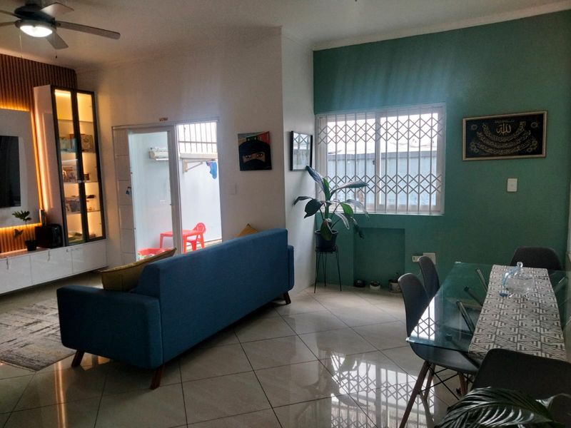 Open-plan living and dining area featuring tiled floors, a ceiling fan, and a built-in display cabinet with integrated lighting.