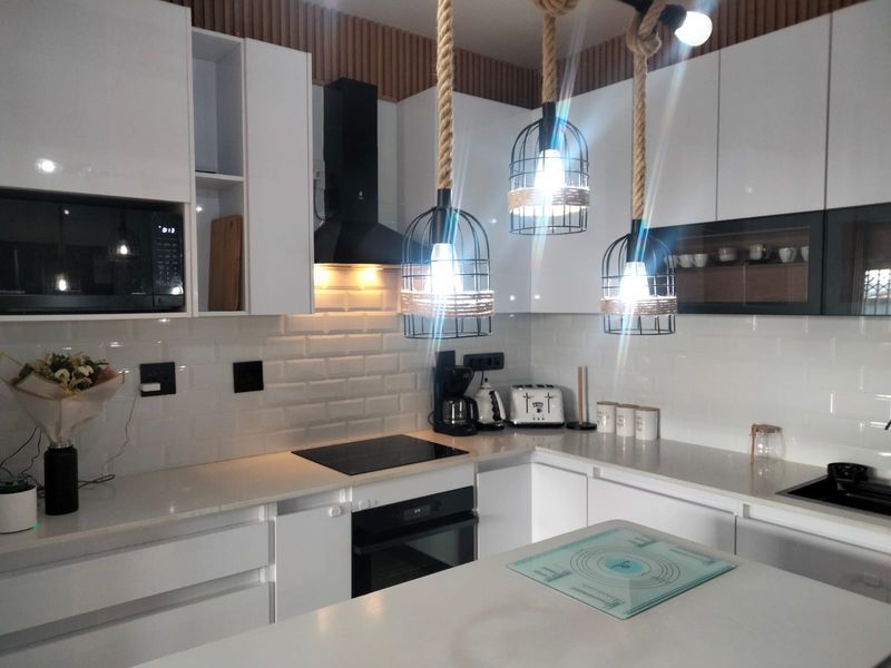 Modern kitchen featuring white cabinetry, quartz countertops, subway tile backsplash, and integrated appliances including an oven, hob, and microwave.