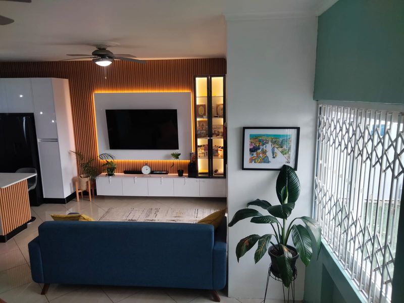 Modern open-plan living area featuring custom slatted wood wall paneling, integrated LED lighting, built-in cabinetry, and secure window gates.