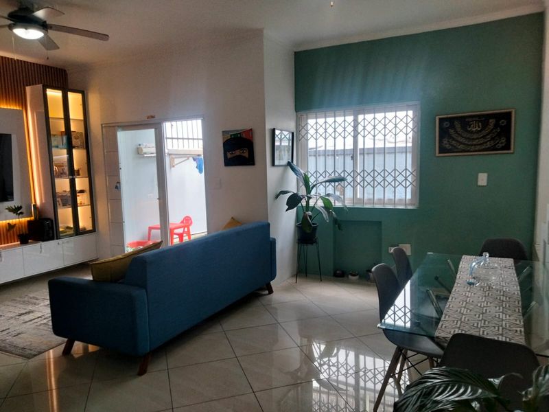 Open-plan living and dining area featuring tiled floors, a ceiling fan, and built-in display cabinetry, with direct access to an outdoor patio area.