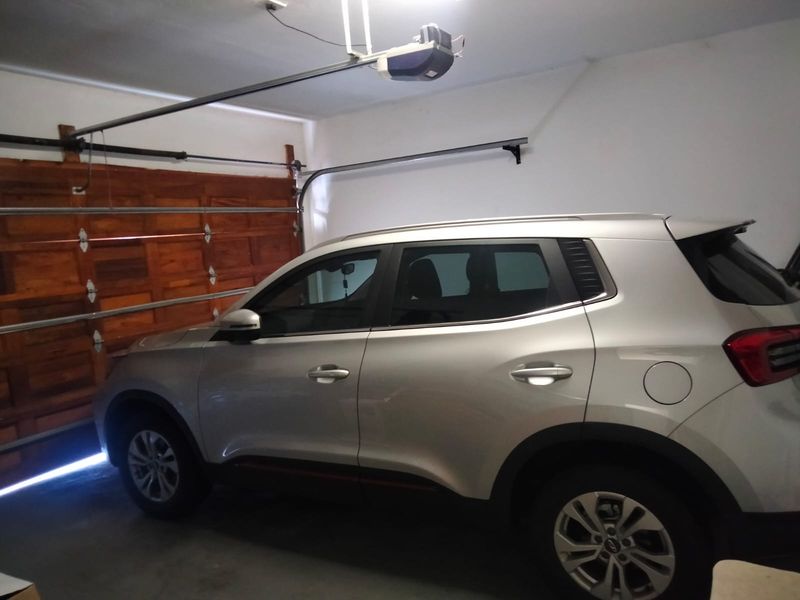 A functional garage space featuring a wooden sectional door and an automatic overhead opener system.