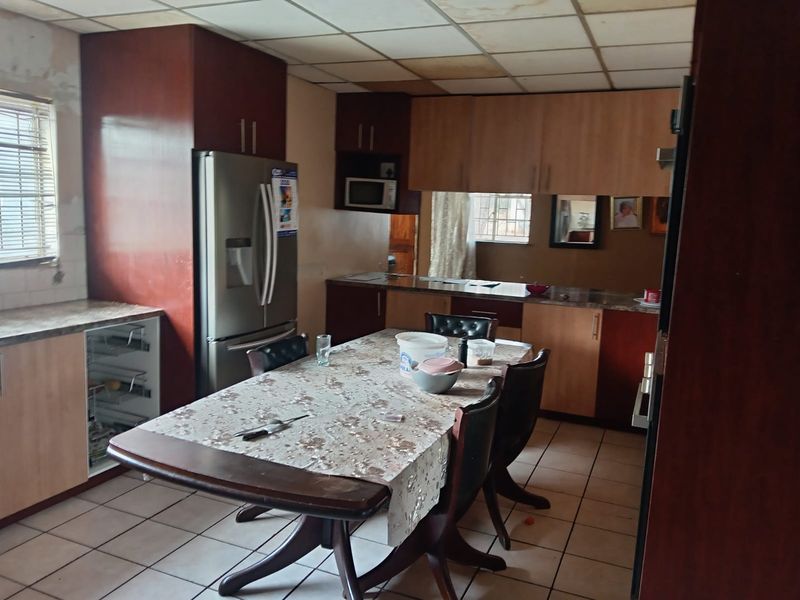 Open plan kitchen and dining area featuring tiled flooring, built-in cabinetry, and a drop ceiling, requiring cosmetic updates to modernize the space.