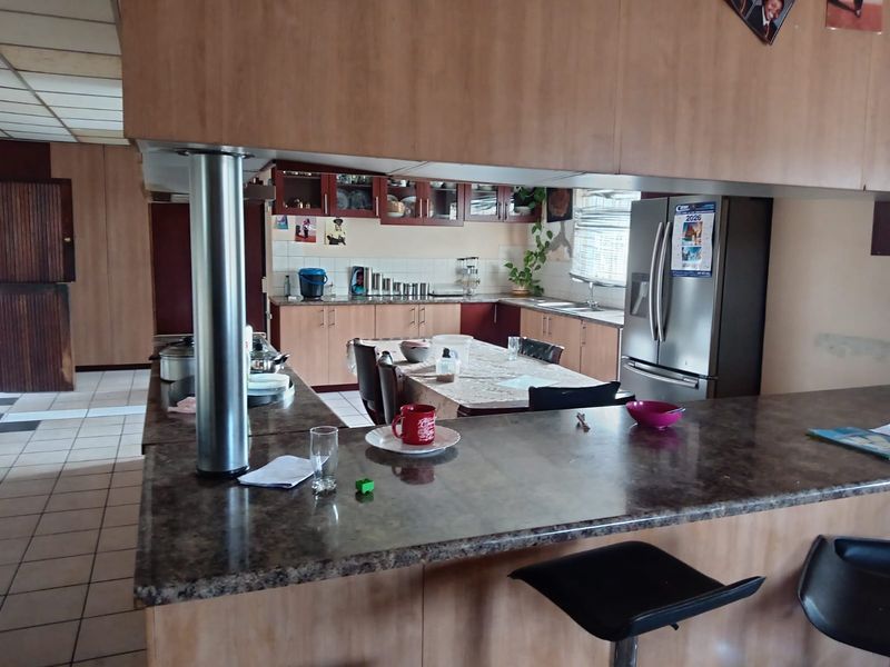 Open plan kitchen and dining area featuring laminate cabinetry, stone-look countertops, and tiled flooring, offering a functional layout for family living.
