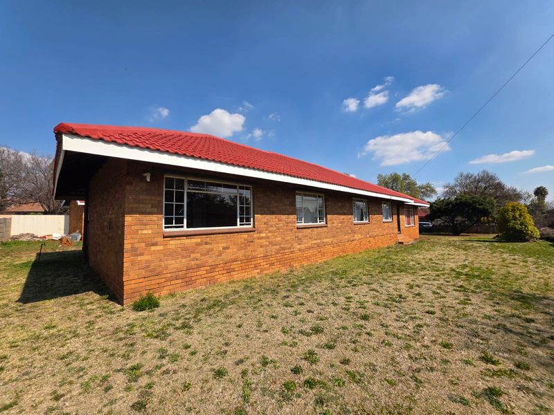 A view of the rear exterior of the house featuring a classic face brick facade and a red tiled roof set against a large lawn.