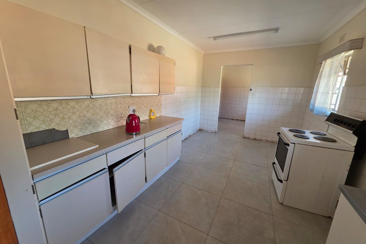 A dated kitchen featuring tiled flooring, tiled splashbacks, and original cabinetry, offering significant potential for a modern renovation and layout update.