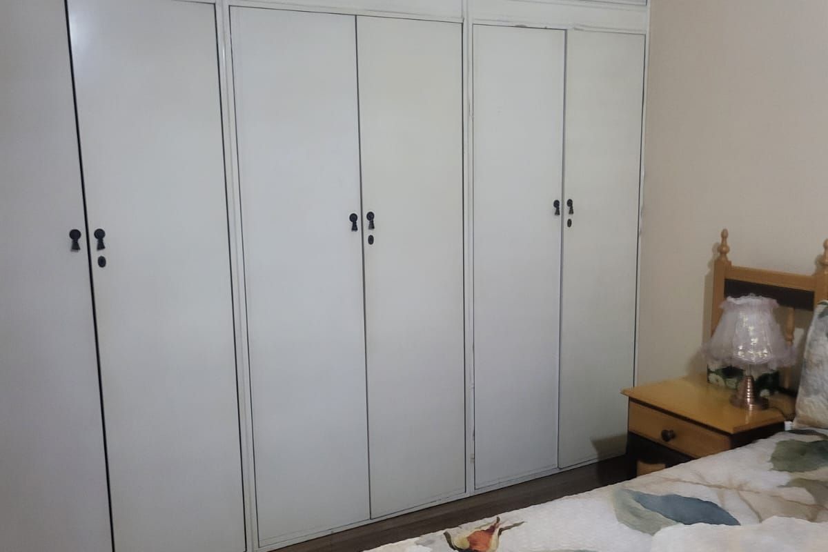 A bedroom featuring extensive floor-to-ceiling built-in cupboards with white cabinetry and traditional hardware.