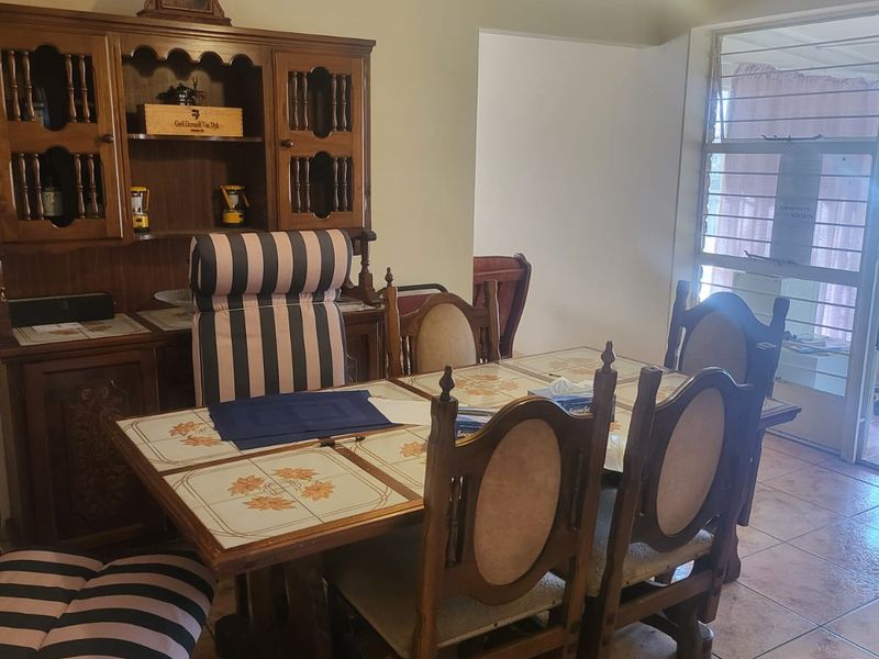 A dining room featuring tiled flooring, a pendant light fixture, and louvered windows with an integrated security gate.