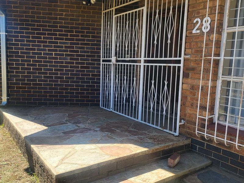 Front entrance featuring a stone-paved porch, brick facade, and security gate, providing a secure and traditional entry point to the home.