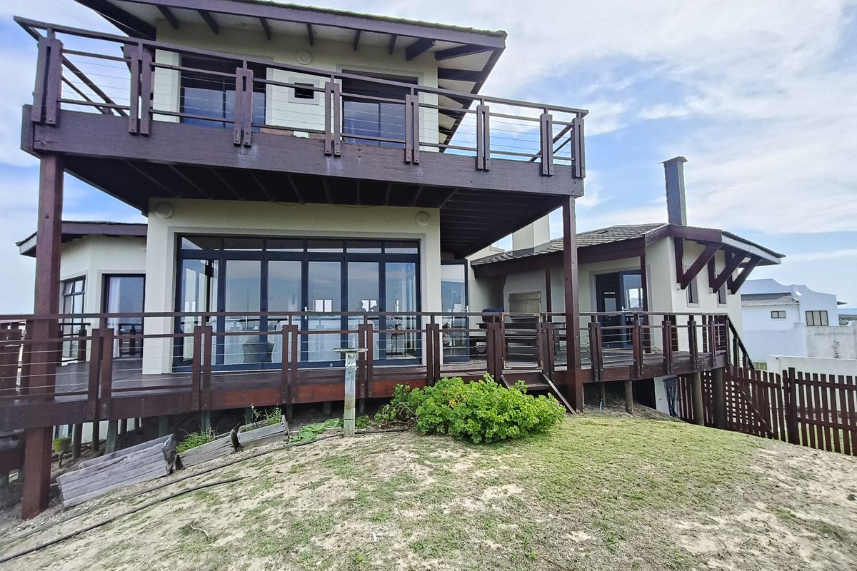 Rear elevation of a multi-level house featuring extensive timber decking, elevated balconies, and large sliding glass doors overlooking the garden area.