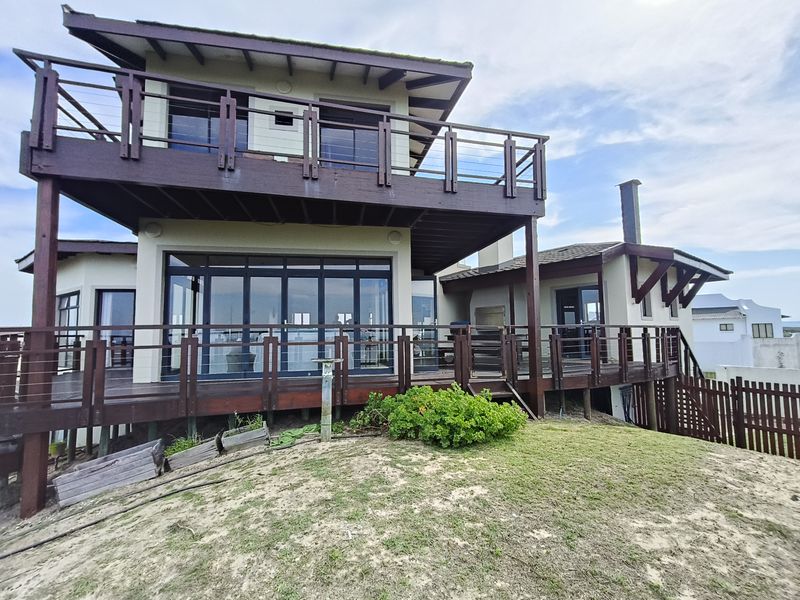 Rear elevation of a multi-level house featuring extensive timber decking, elevated balconies, and large sliding glass doors overlooking the garden area.