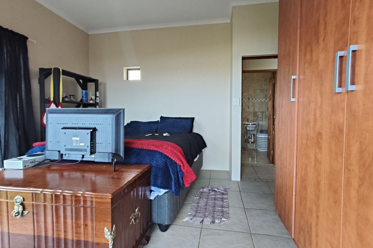 A bedroom featuring tiled flooring, built-in wooden cupboards, and direct access to an en-suite bathroom.