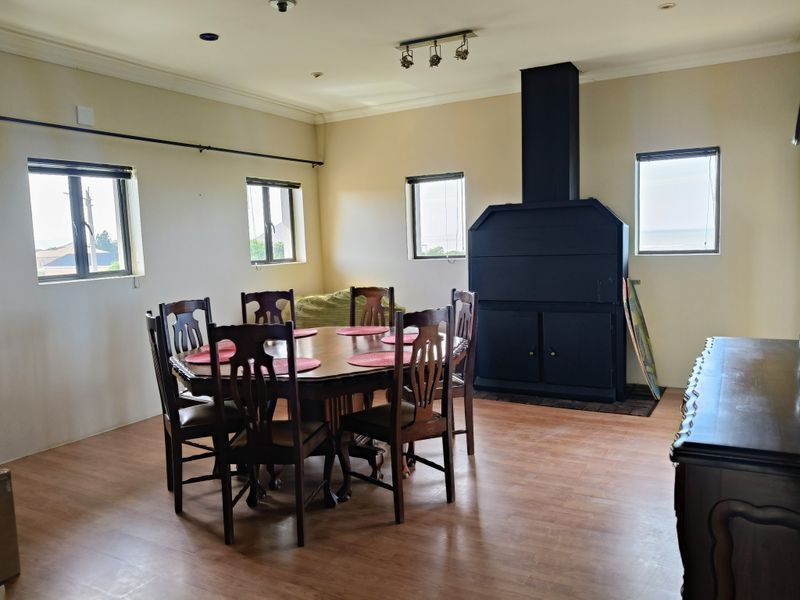 Spacious dining room featuring laminate flooring, recessed and track lighting, and a prominent built-in fireplace with a black chimney breast.