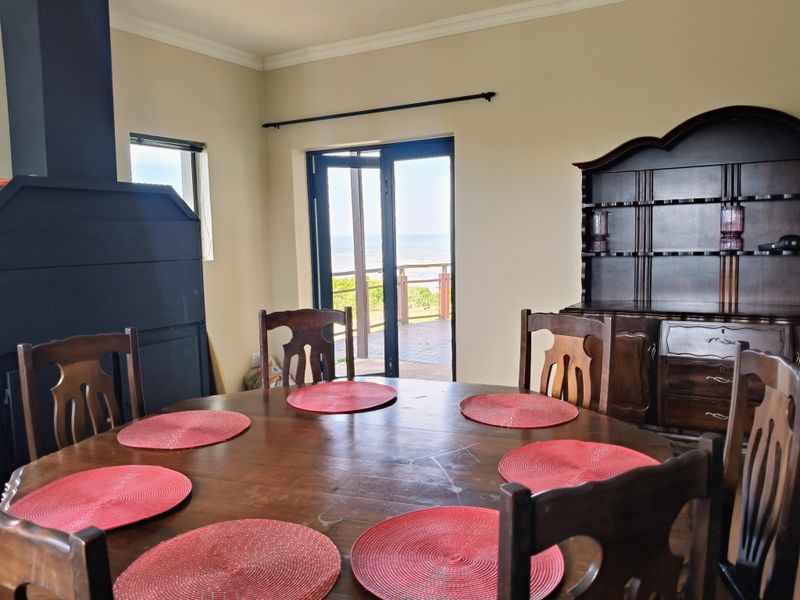 Dining room featuring a built-in fireplace, crown molding, and double glass doors providing access to an outdoor deck with ocean views.
