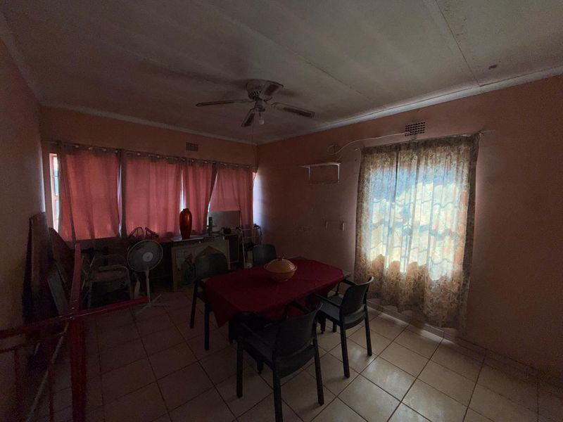 A dining room featuring tiled flooring and a ceiling fan, requiring cosmetic updates to improve the overall aesthetic and brightness of the space.
