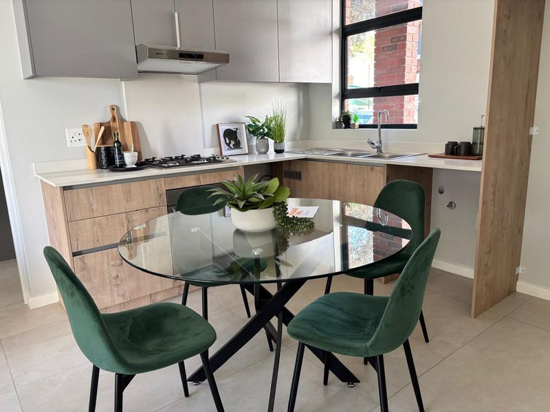 Modern open-plan kitchen featuring wood-look cabinetry, stone countertops, integrated gas hob, and extractor fan, seamlessly flowing into a dining area with tiled floors.