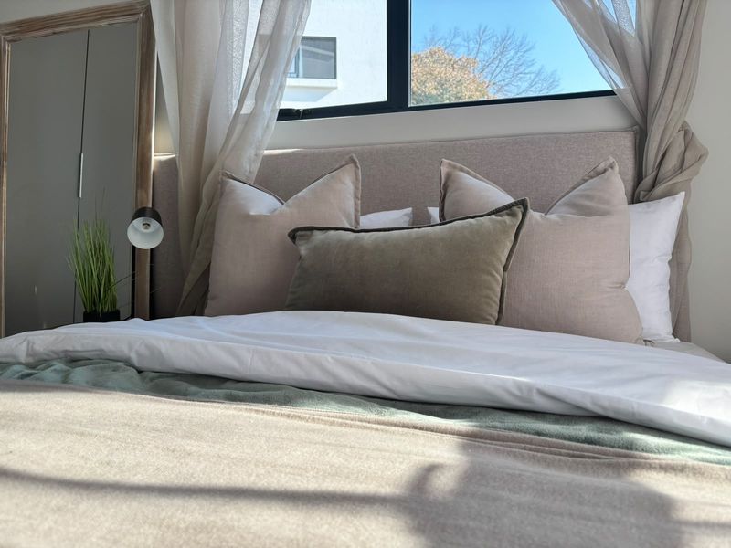 A well-lit bedroom featuring a large window and built-in wardrobe, creating a bright and comfortable sleeping space.