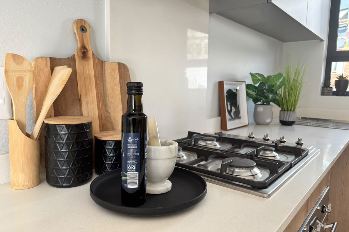 Modern kitchen featuring a clean stone countertop, integrated gas hob, and sleek glass splashback with contemporary cabinetry.