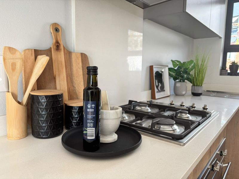 Modern kitchen featuring a clean stone countertop, integrated gas hob, and sleek glass splashback with contemporary cabinetry.