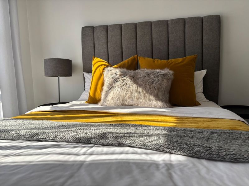 A well-lit bedroom featuring a modern upholstered headboard and neutral wall finishes.