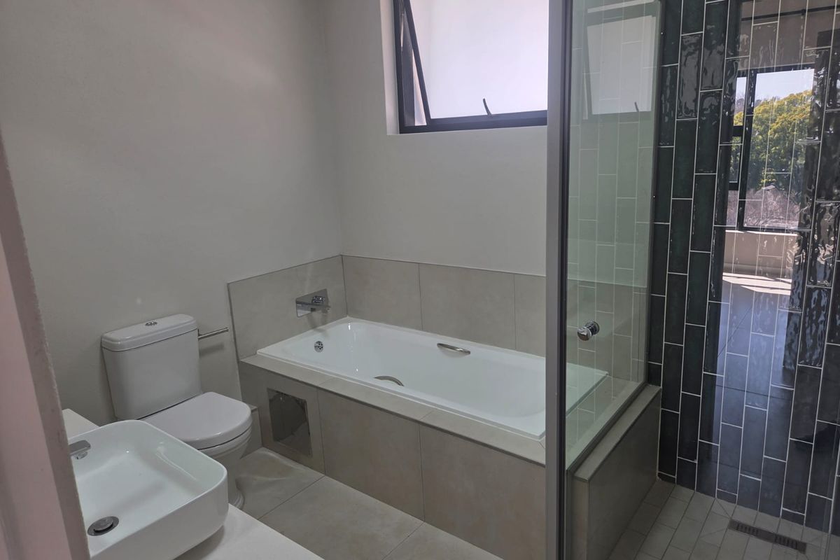 Modern bathroom featuring a built-in bathtub, separate glass-enclosed shower, wall-mounted basin, and contemporary tiled finishes.