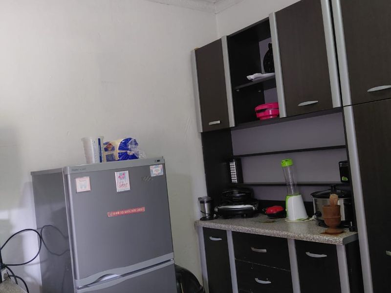 A functional kitchen area featuring dark built-in cabinetry, laminate countertops, and a gas hob, offering a practical layout for daily meal preparation.