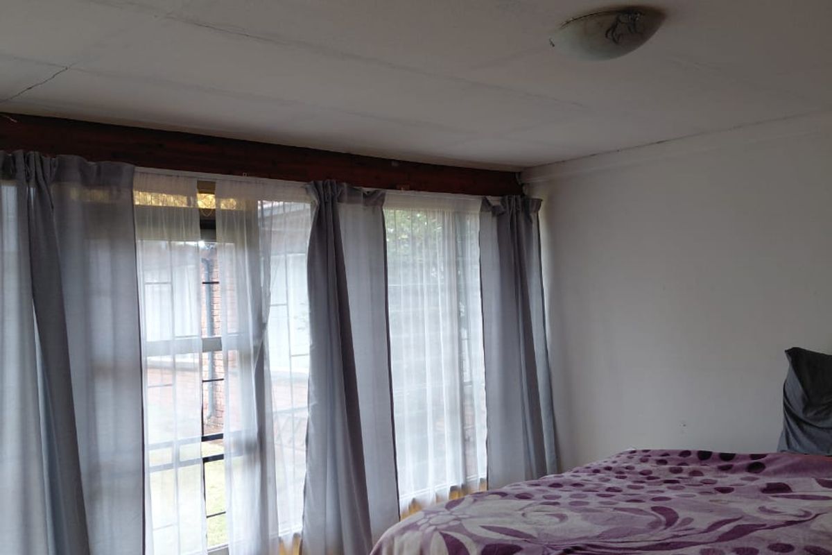 A bedroom featuring tiled flooring and a ceiling with visible tile joints, providing a functional space with potential for cosmetic updates.