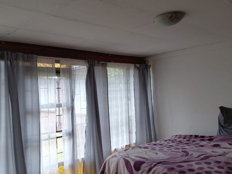 A bedroom featuring tiled flooring and a ceiling with visible tile joints, providing a functional space with potential for cosmetic updates.