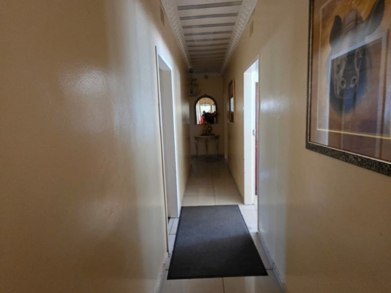 A long residential hallway featuring tiled flooring and decorative ceiling detailing, providing access to multiple rooms within the home.