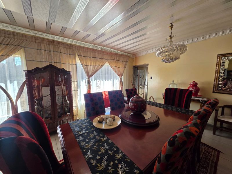 A traditional dining room featuring decorative ceiling paneling, crown molding, and a central chandelier, providing a classic foundation for a formal dining space.
