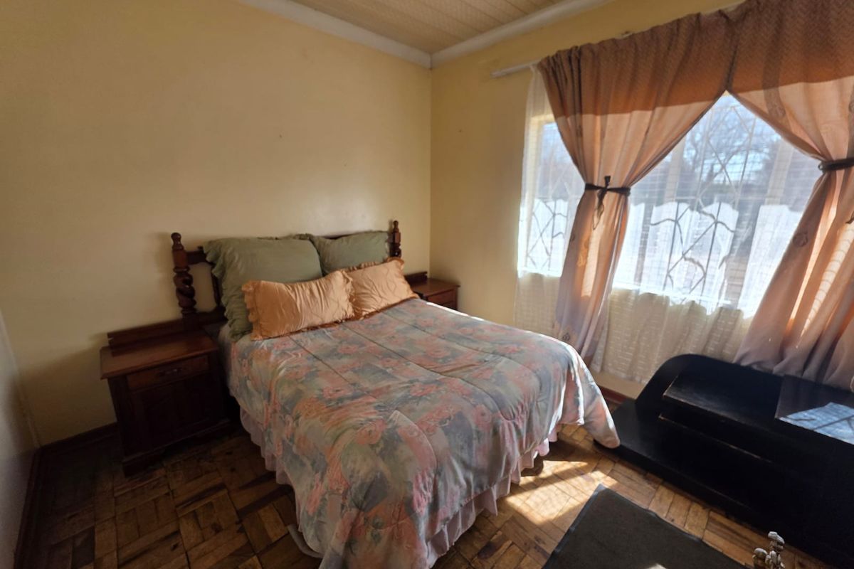 A bedroom featuring traditional parquet flooring and a timber ceiling, offering a dated aesthetic with potential for modernization.