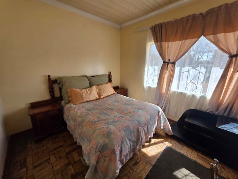 A bedroom featuring traditional parquet flooring and a timber ceiling, offering a dated aesthetic with potential for modernization.