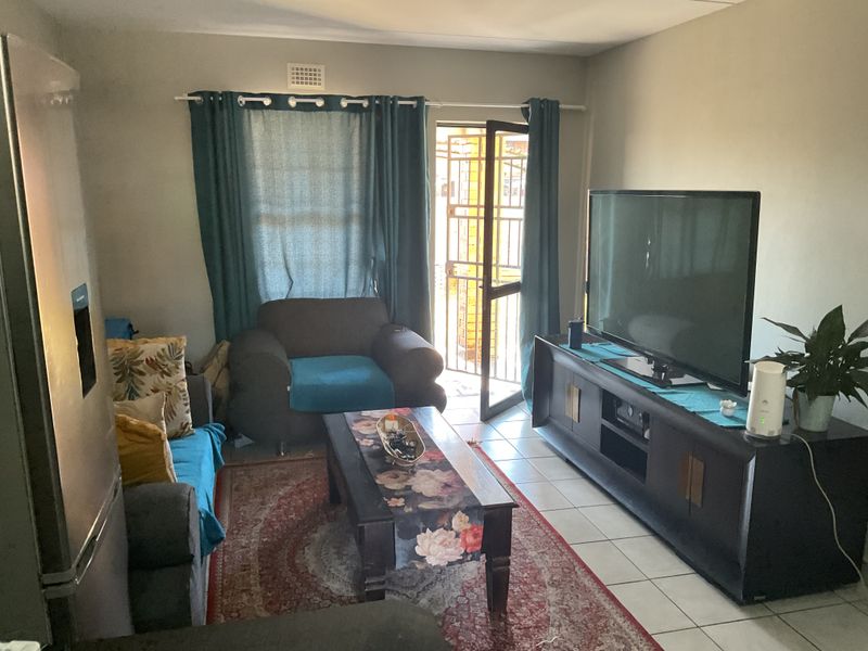 A living room featuring tiled flooring and direct access to an outdoor area through a security gate.