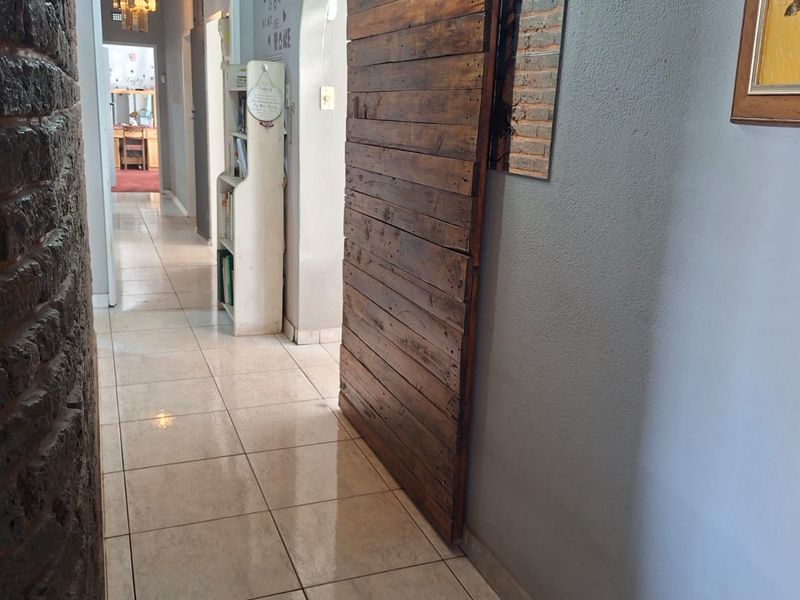 A tiled hallway featuring an exposed brick wall, a rustic sliding barn door, and an arched transition leading to adjacent living spaces.