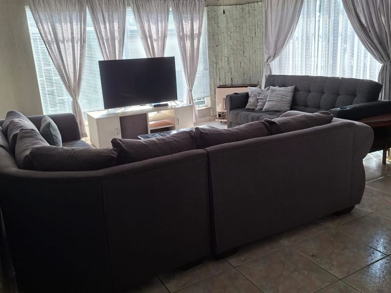 Spacious living room featuring tiled flooring, a textured ceiling with a fan, and a decorative stone feature wall.