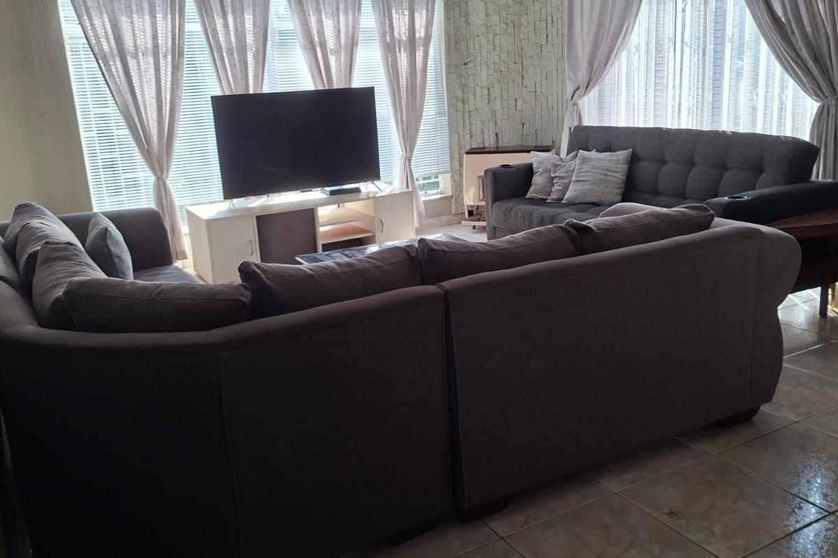 Spacious living room featuring tiled flooring, a textured ceiling with a fan, and a decorative stone feature wall.