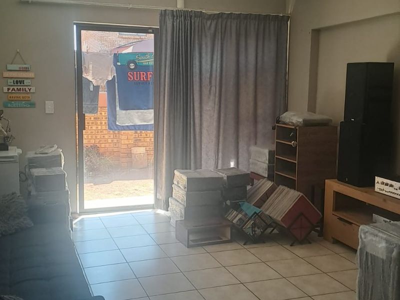 A living room featuring tiled flooring and a sliding glass door providing access to an outdoor area.